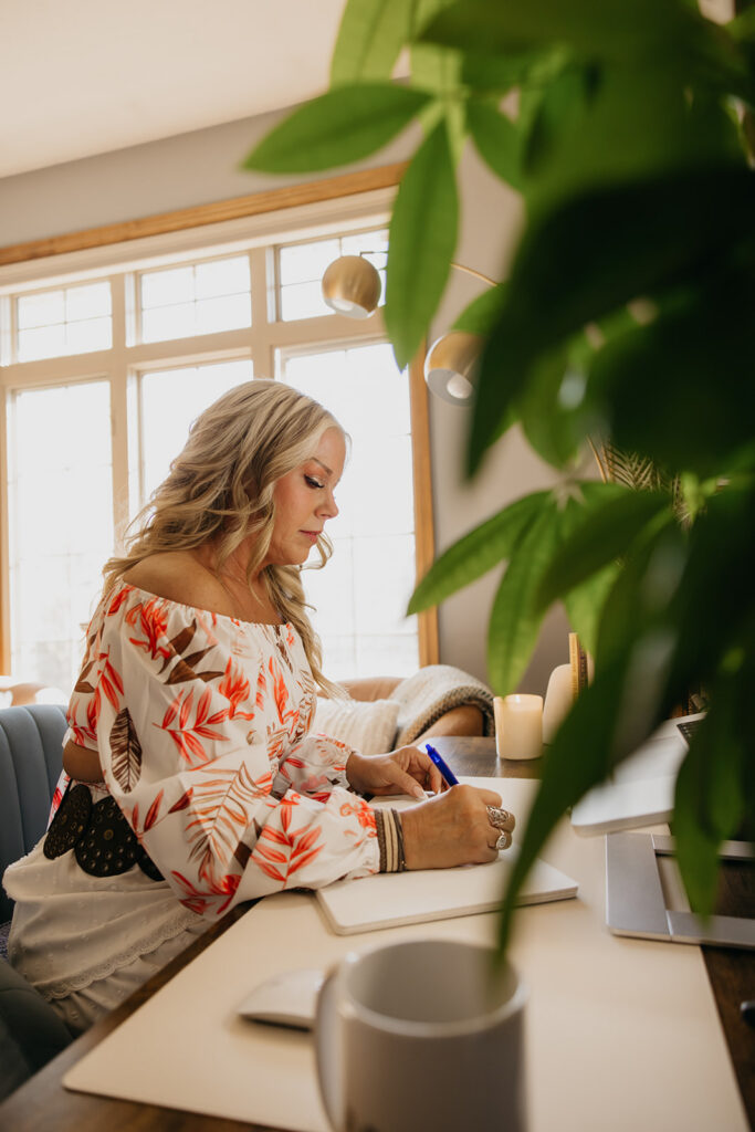 Women's mentor writing in a journal at her desk surrounded by natural light during Minneapolis brand shoot
