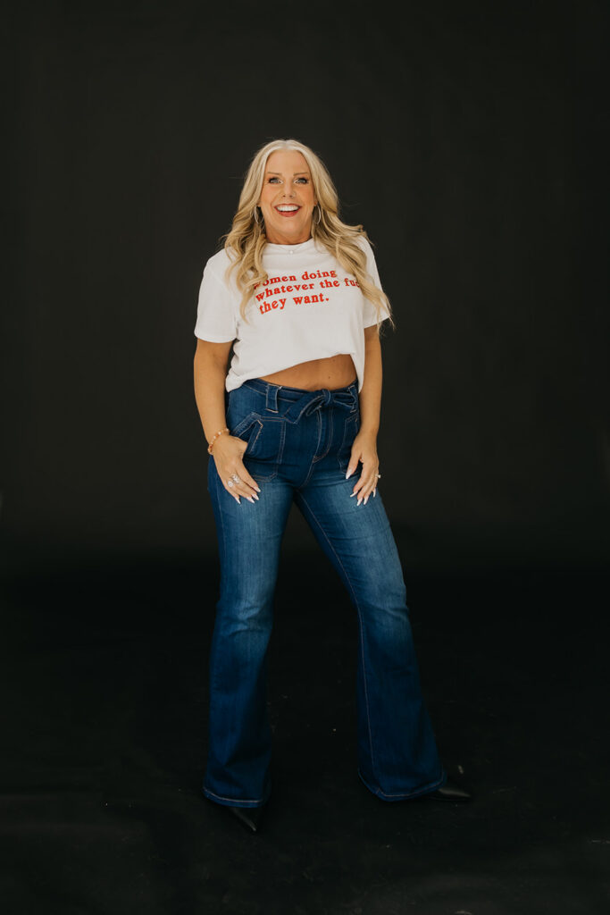 Women's wellness coach in statement graphic tee and jeans posing during brand photography session in Minneapolis