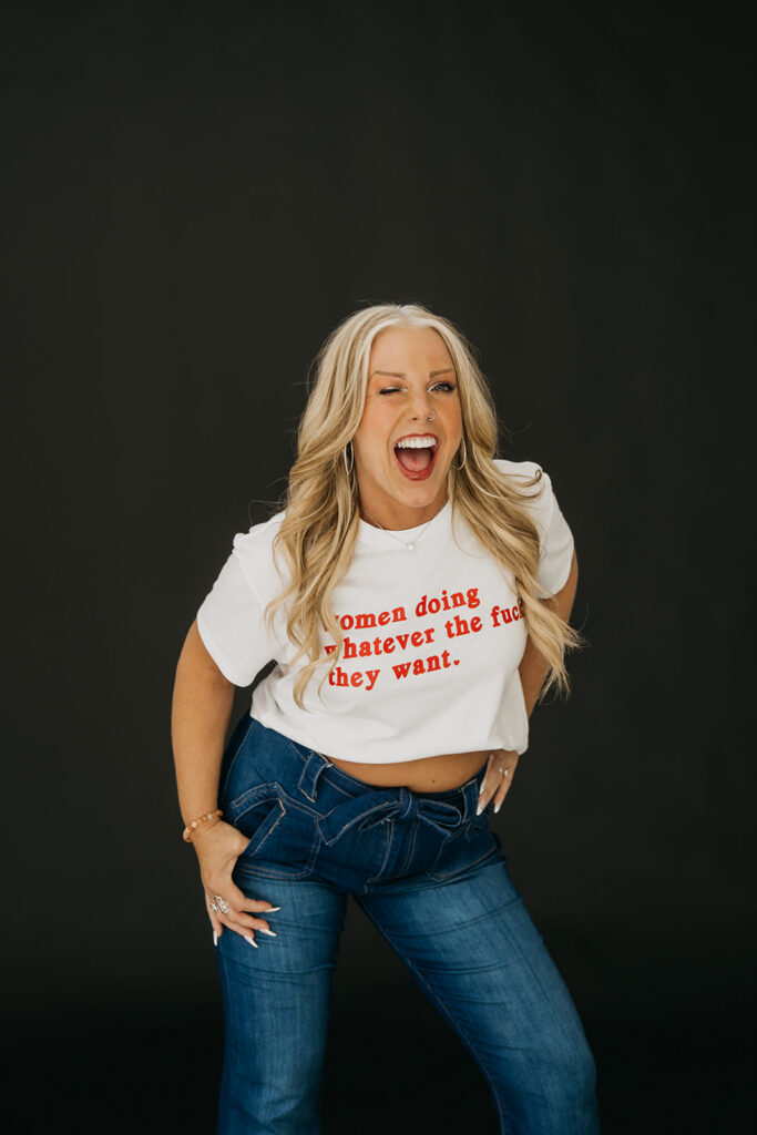 Women's wellness coach throwing her head back laughing in a statement graphic tee during brand photography session