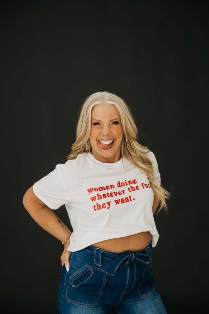 Women's mentor in graphic tee posing with attitude during brand photography session on dark studio backdrop