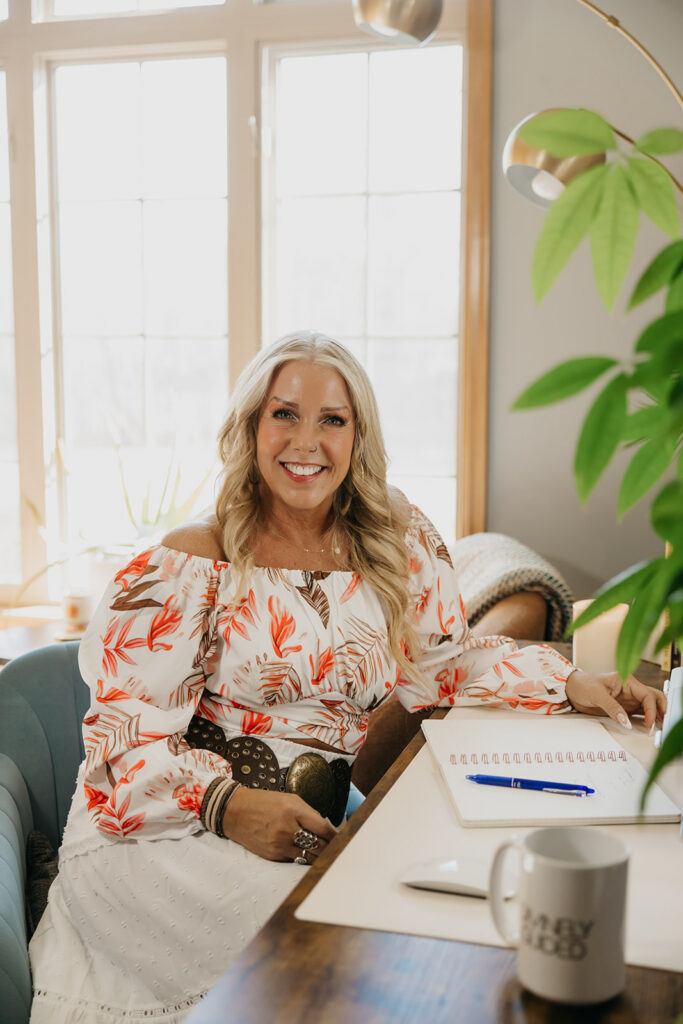 Women's mentor smiling while holding a mug at her desk during Laughing Lotus brand photo session in Minneapolis