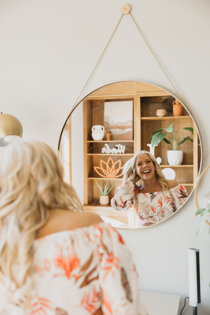 Women's wellness coach reflected in a round mirror while smiling during brand photography shoot