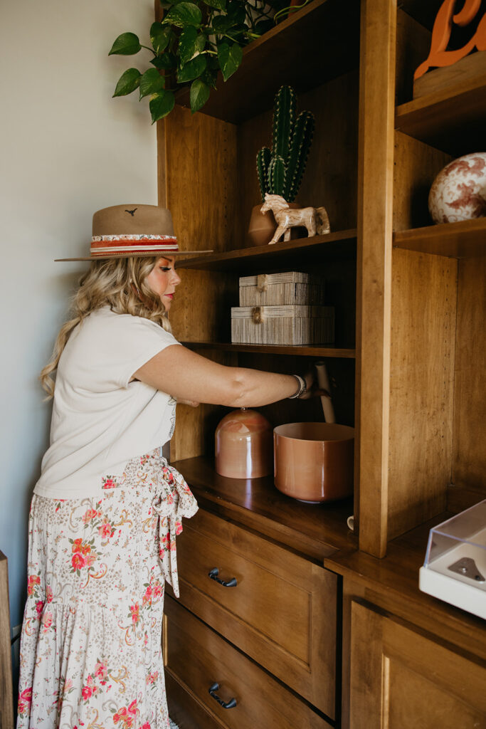 Women's energy healer reaching into wooden shelving in her healing studio during Laughing Lotus brand session