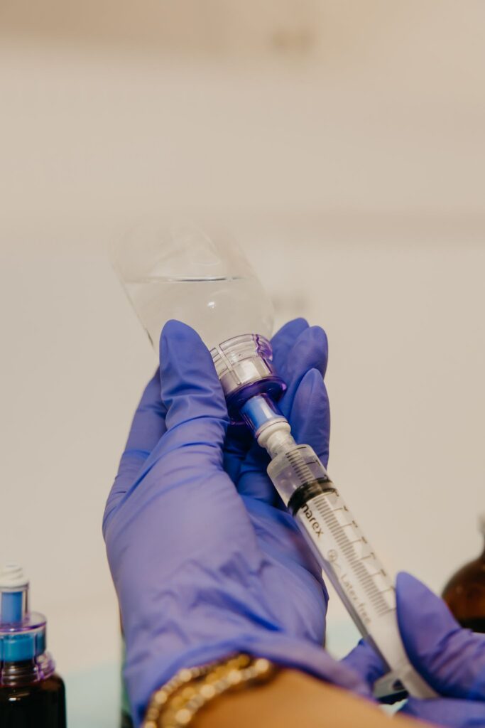 Gloved hand preparing syringe during integrative medicine brand photography session Minneapolis