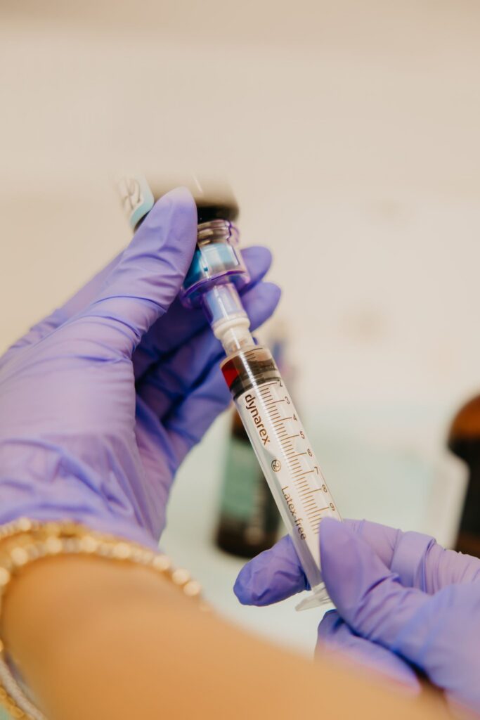 Gloved hand administering injection during integrative medicine brand photography session Minneapolis
