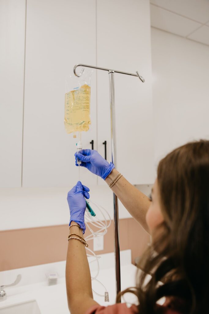 Gloved hand adjusting IV drip stand during integrative medicine brand photography Minneapolis
