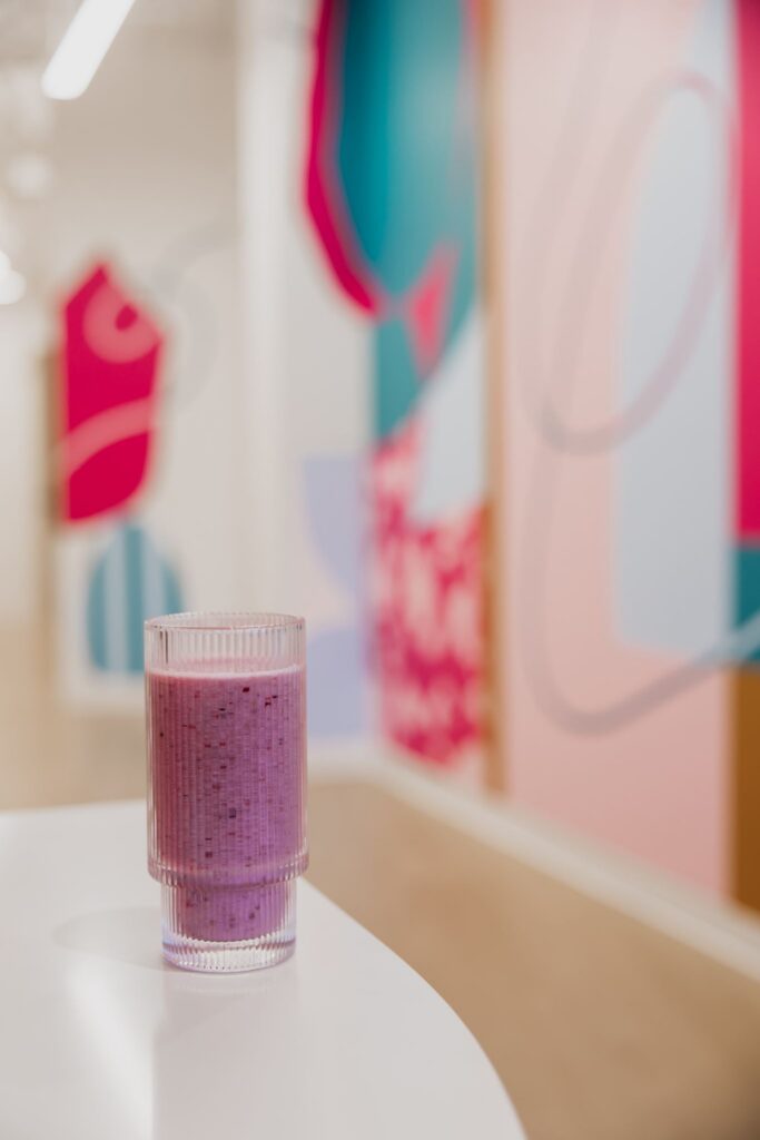 Purple wellness smoothie in front of colorful art wall during MIMC brand photography Minneapolis