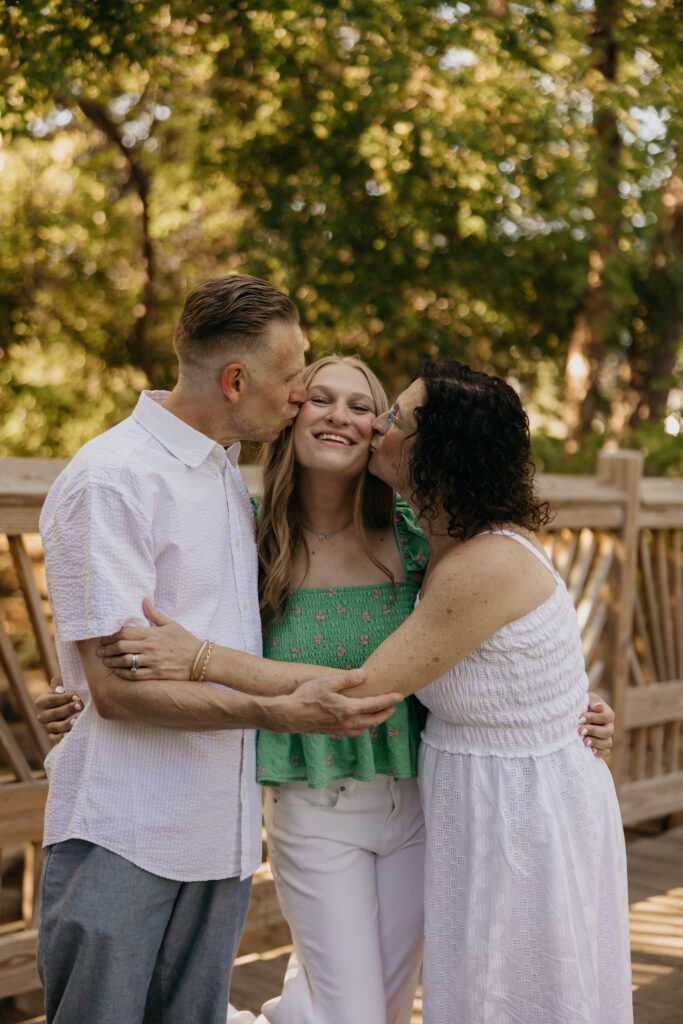 Hopkins High School senior girl being kissed on cheek by family member during outdoor senior session