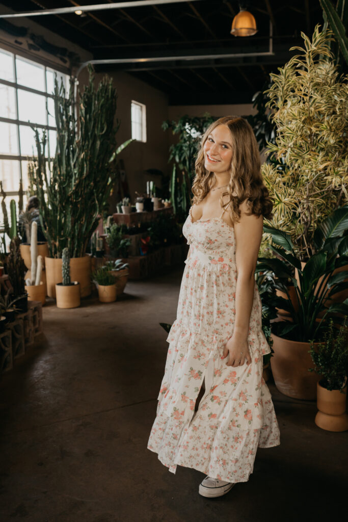 Hopkins senior photos of girl in floral maxi dress walking through cactus-filled Minneapolis plant shop
