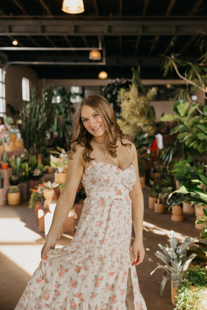 Hopkins High School senior girl swishing floral maxi dress skirt for movement shot at Minneapolis plant shop