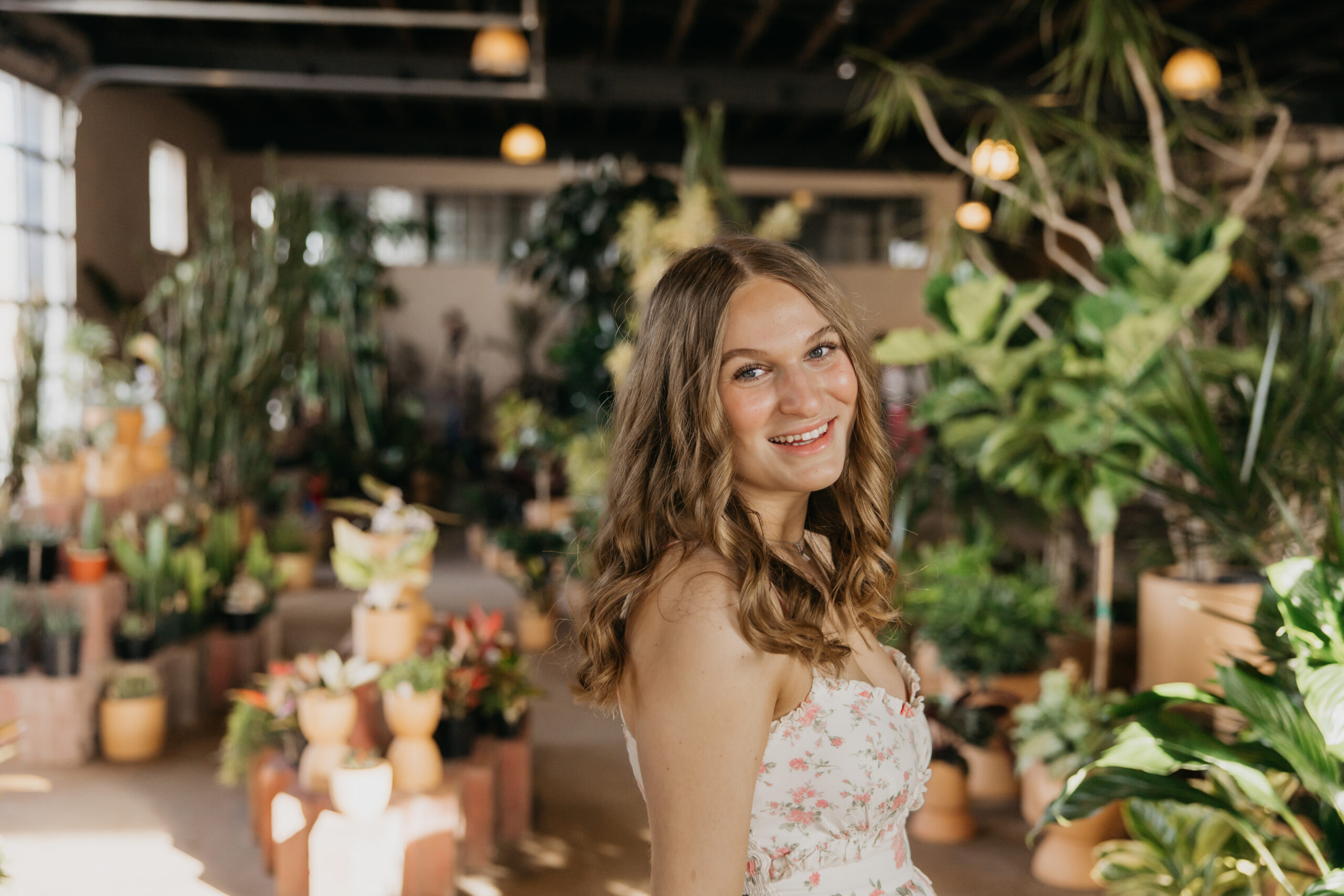 Hopkins senior photos close-up of girl smiling over her shoulder surrounded by greenery at a Minneapolis plant shop
