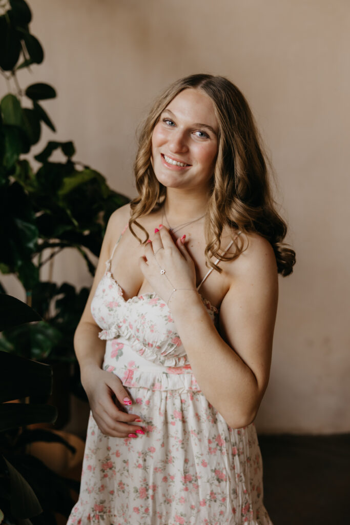 Hopkins senior photos close-up of girl in floral dress with hand near collarbone at Minneapolis plant shop
