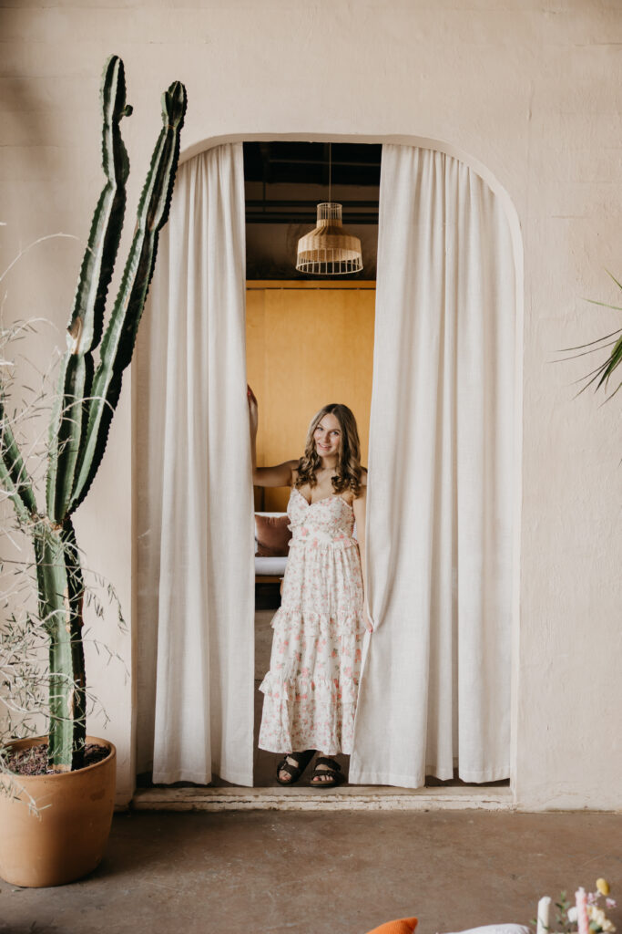 Hopkins senior photos of girl in floral maxi dress standing in curtained arched doorway next to tall cactus