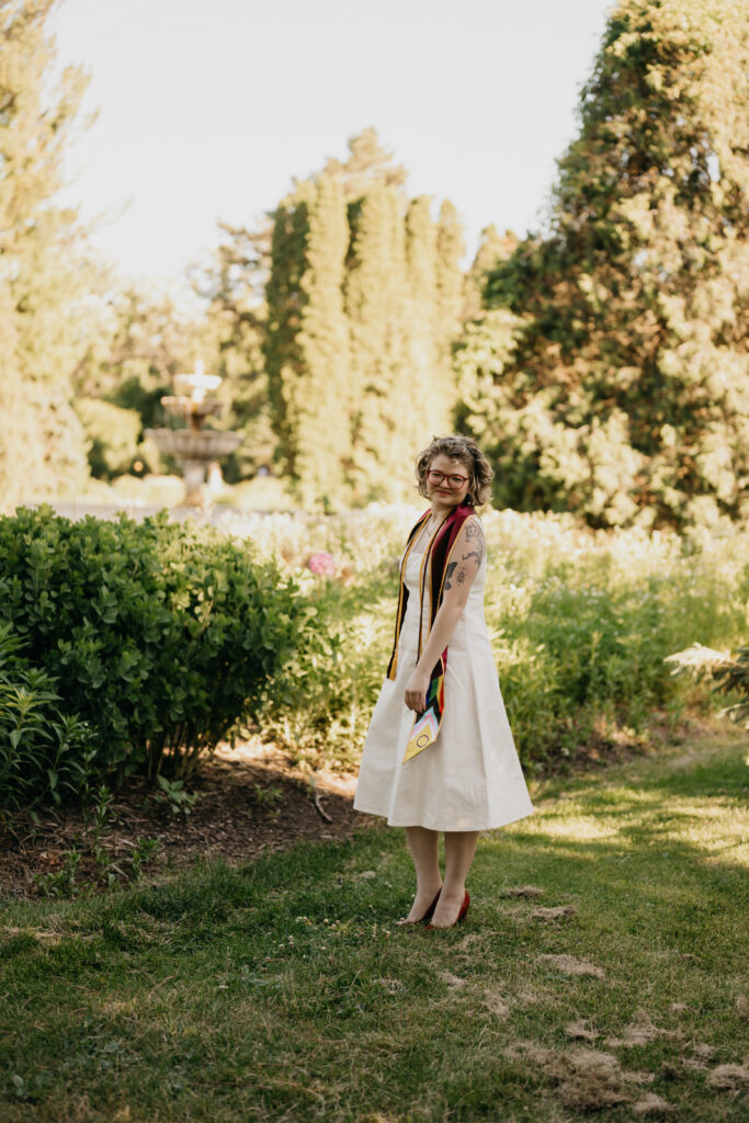 full length shot of graduate walking a garden path near the fountain