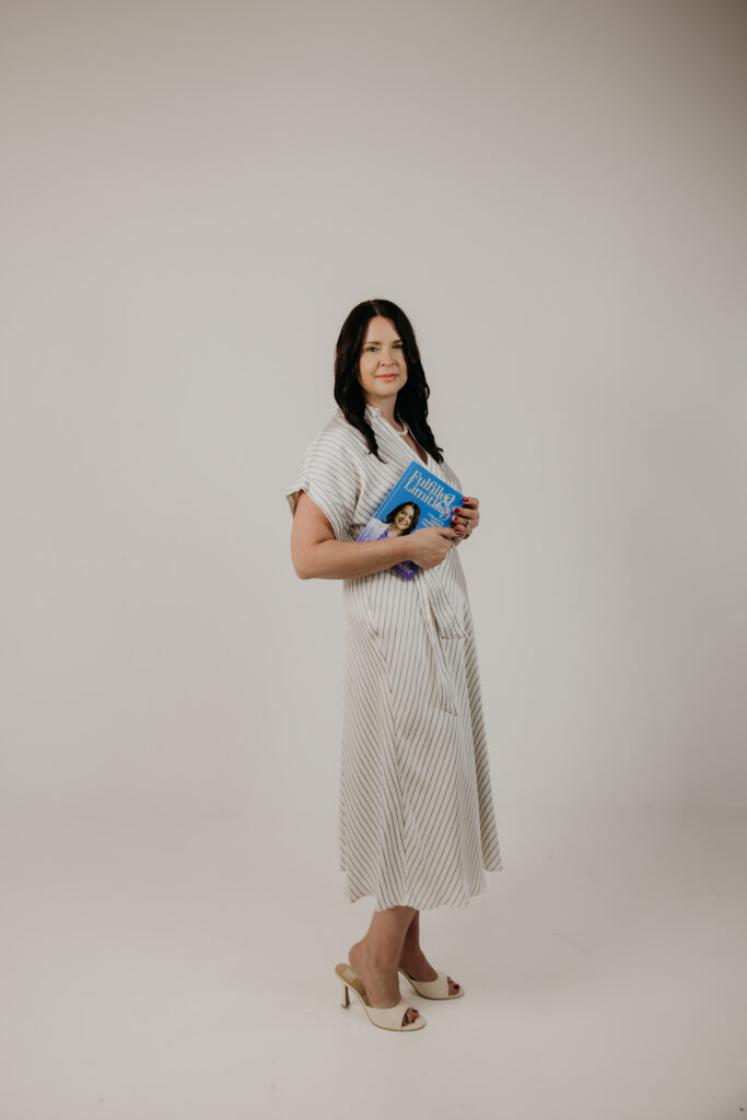 Christi Cossette standing in a studio holding her book, brand photography portrait