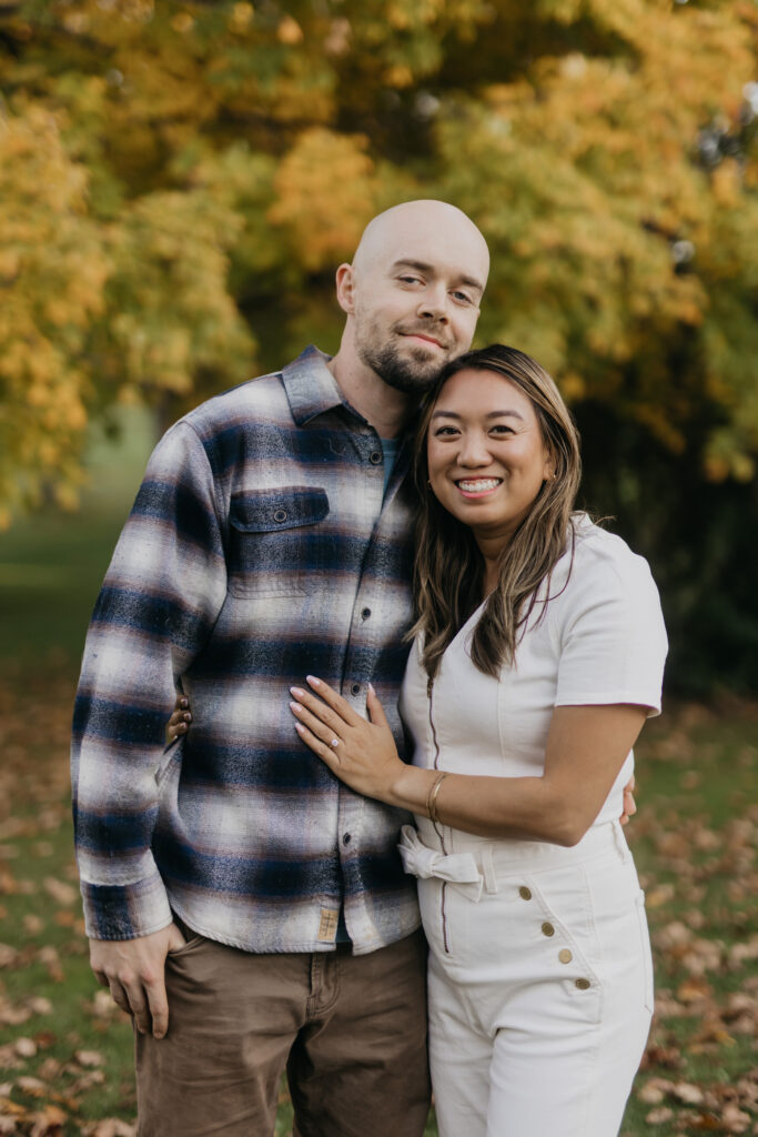 Couple smiling close together, man in plaid flannel, woman in white outfit