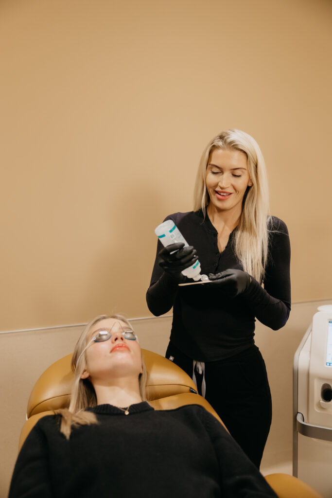 CLEO Skin + Laser esthetician performing laser facial treatment on client in treatment chair
