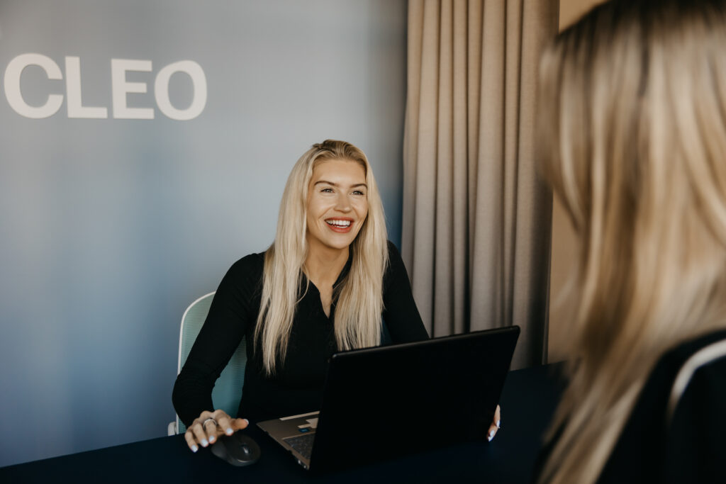 CLEO Skin + Laser staff member smiling while working on laptop at consultation desk