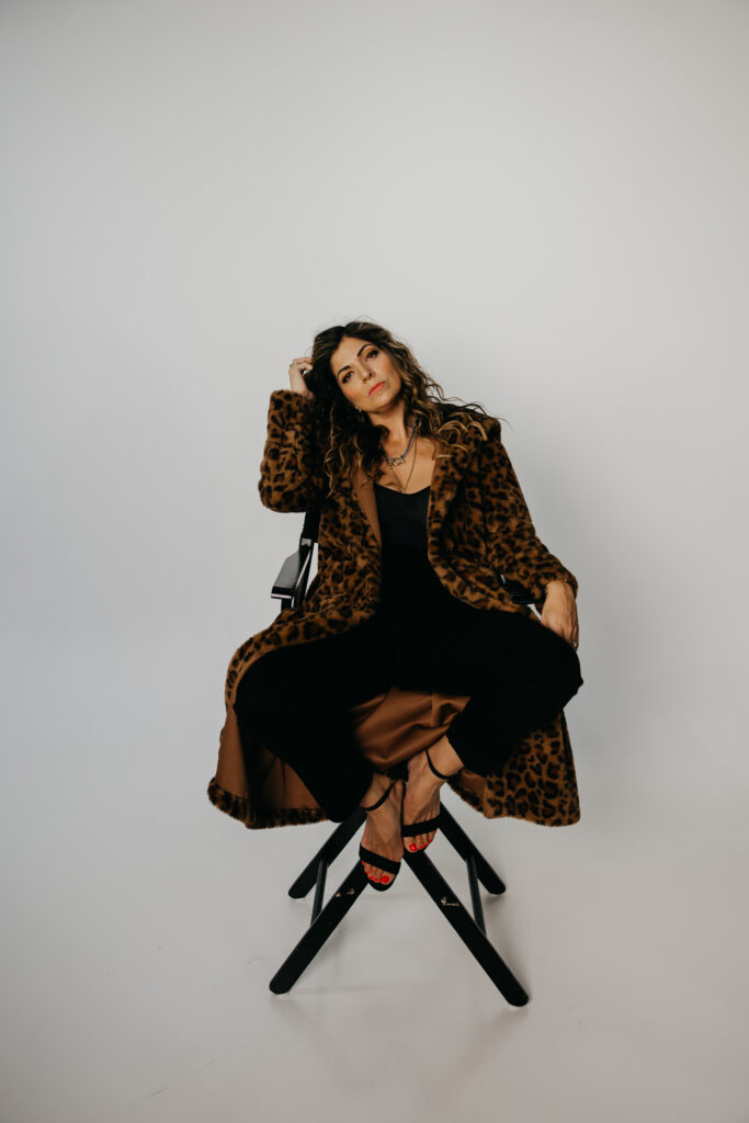 Woman in a leopard coat sitting on a stool, editorial brand photography portrait