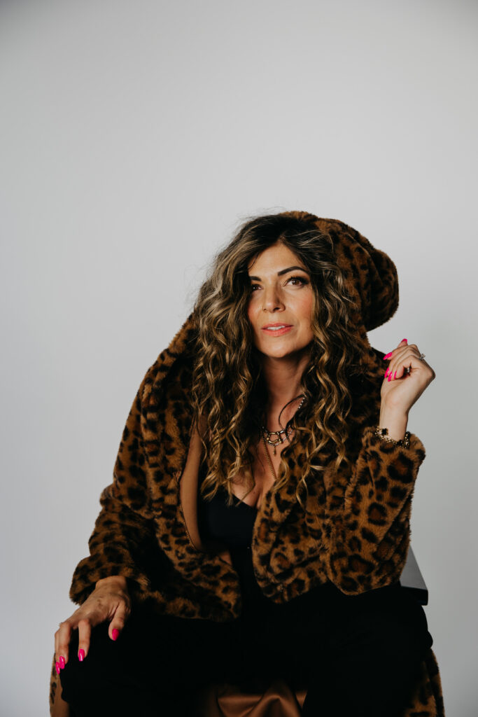 Woman in a leopard coat and hood, dramatic studio brand photography portrait