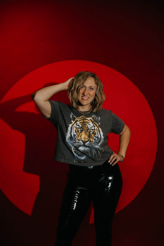 Woman standing with hand on head, dramatic shadow cast under a red spotlight