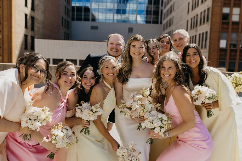 Groom laughing with bridesmaids in a close group photo against the downtown skyline