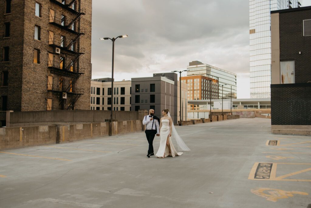 Wide shot of the couple walking together across the rooftop parking structure