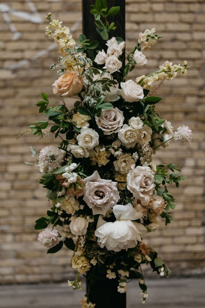 Close-up of the ceremony floral arrangement against the Lumber Exchange Event Center's exposed brick wall