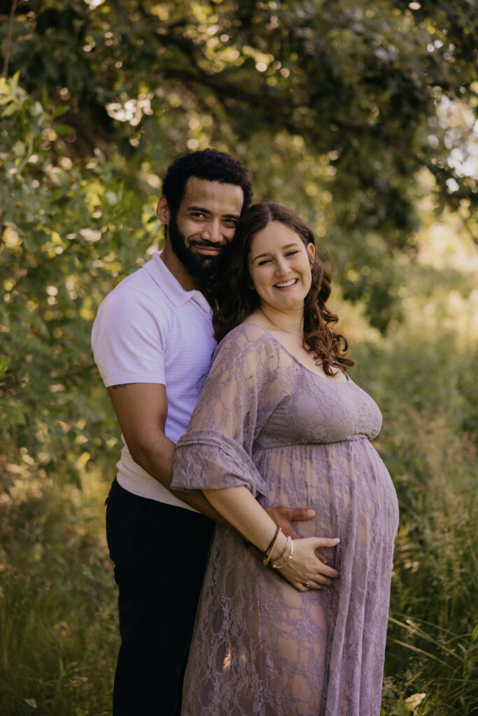 Calvin wrapping his arm around Emily, both smiling, standing in a sunlit field