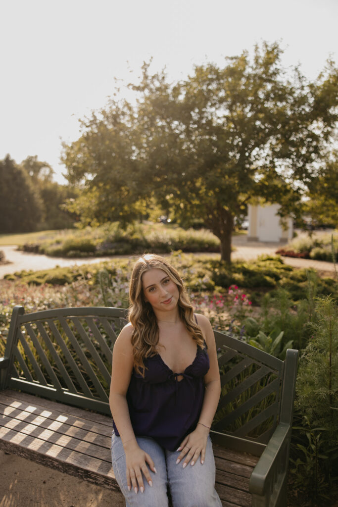 senior girl in navy top sitting on wooden garden bench