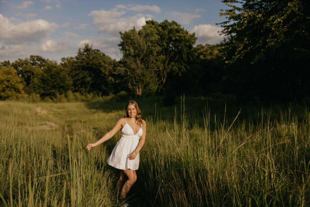 senior girl in white dress standing in tall wildflower field, nature-inspired senior photos