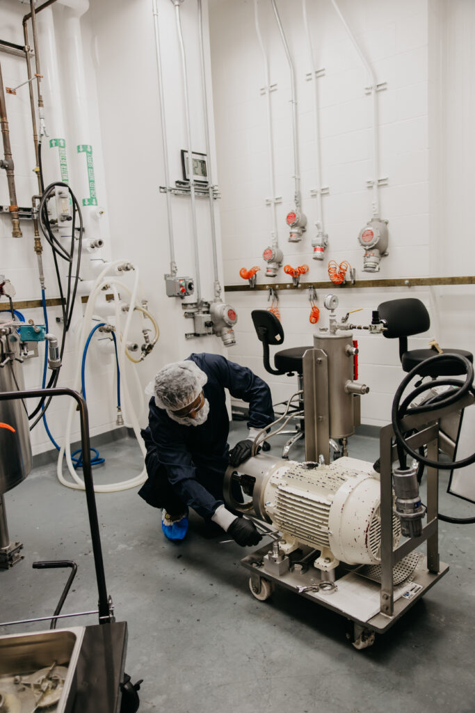 Employee crouched to service a motor and pump unit on the production floor
