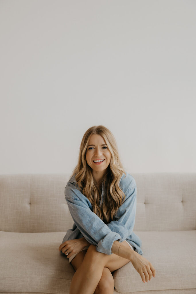 Content creator smiling gently on couch in denim shirt, side profile