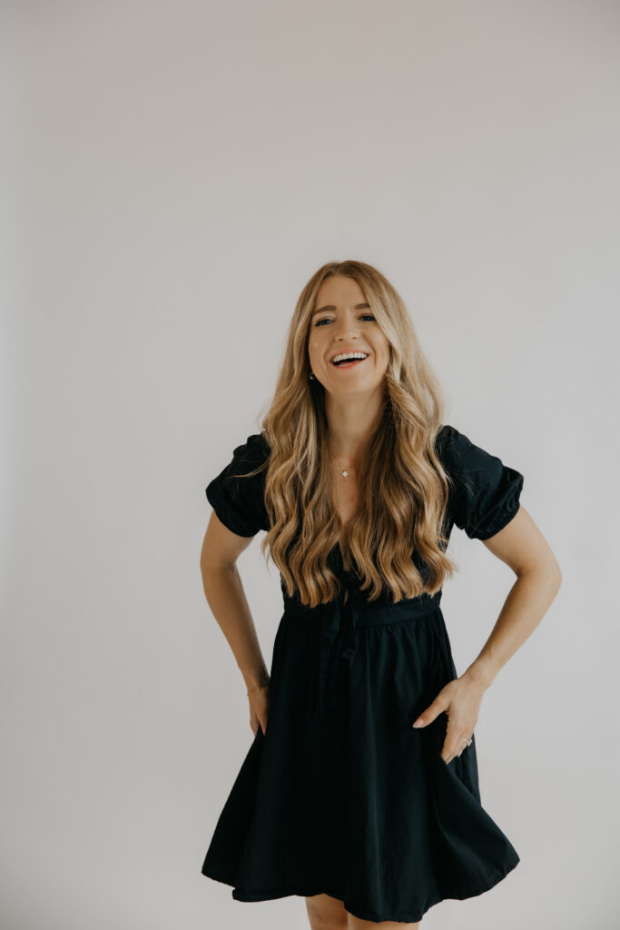 Content creator laughing with hand on hip in black dress