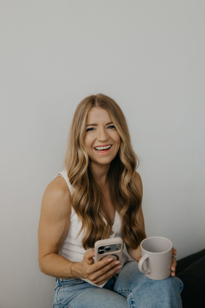 Content creator laughing while holding phone and coffee mug, casual candid moment