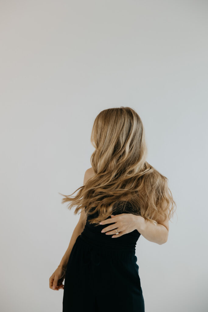 Content creator with hair mid-motion covering face in black jumpsuit