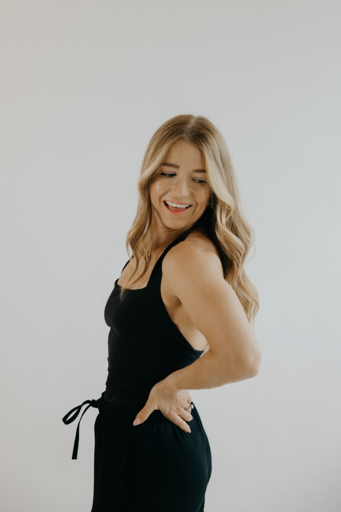 Content creator glancing over shoulder smiling in black jumpsuit