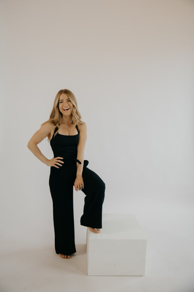Content creator stepping onto white block in black jumpsuit, confident pose