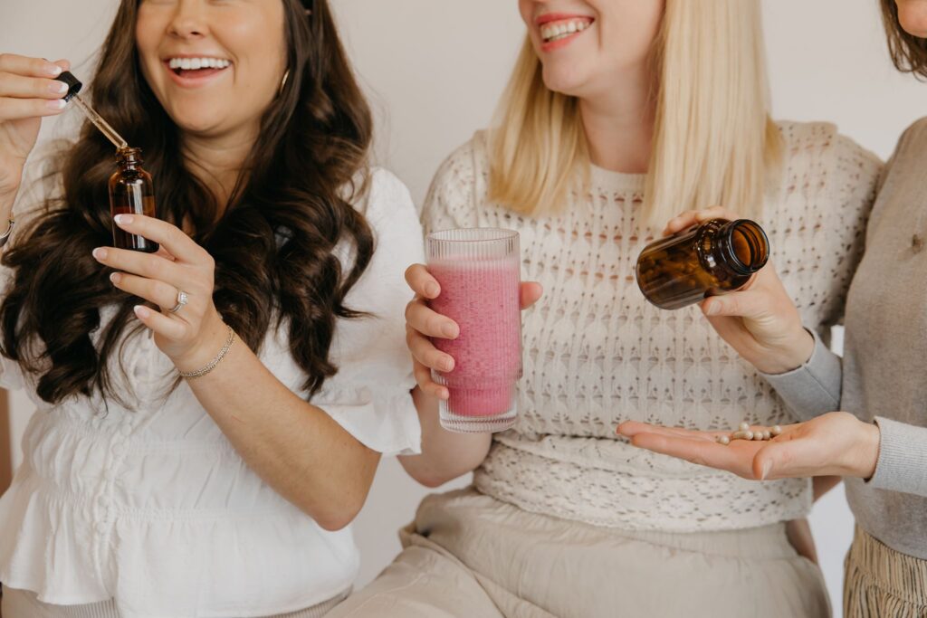Two Minneapolis Integrative Medicine team members laughing while holding tincture dropper and smoothie