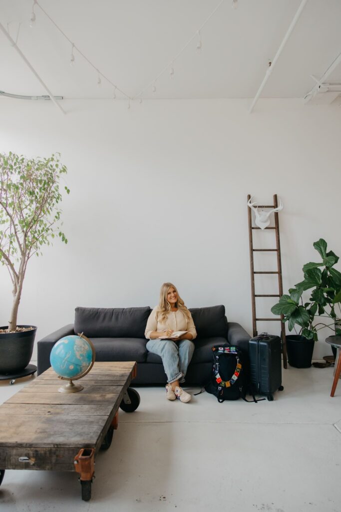 Real estate coach seated near coffee table styled with globe and travel bag