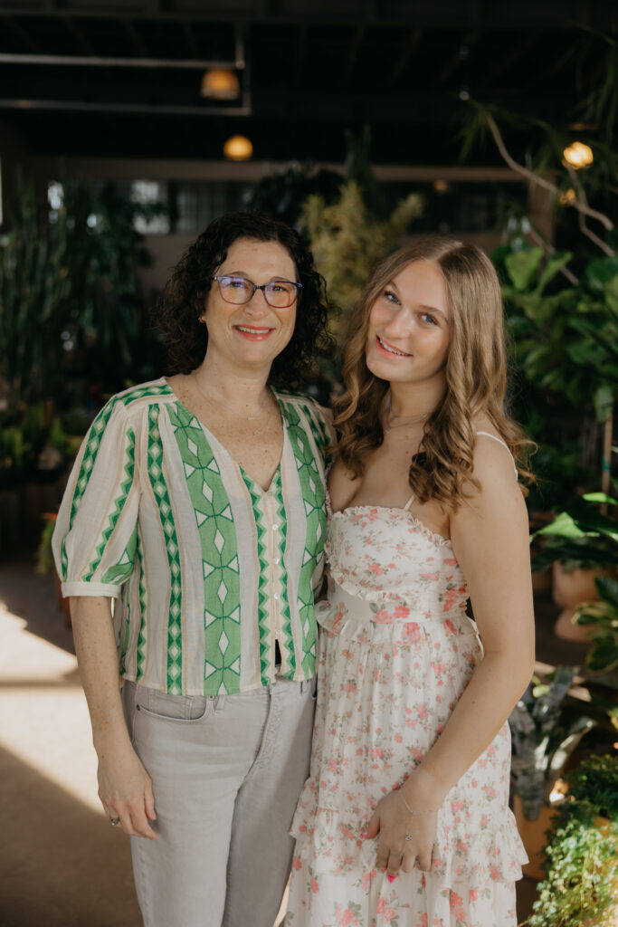 Minneapolis senior and her mom smiling together in a plant-filled studio during senior photography session with mom