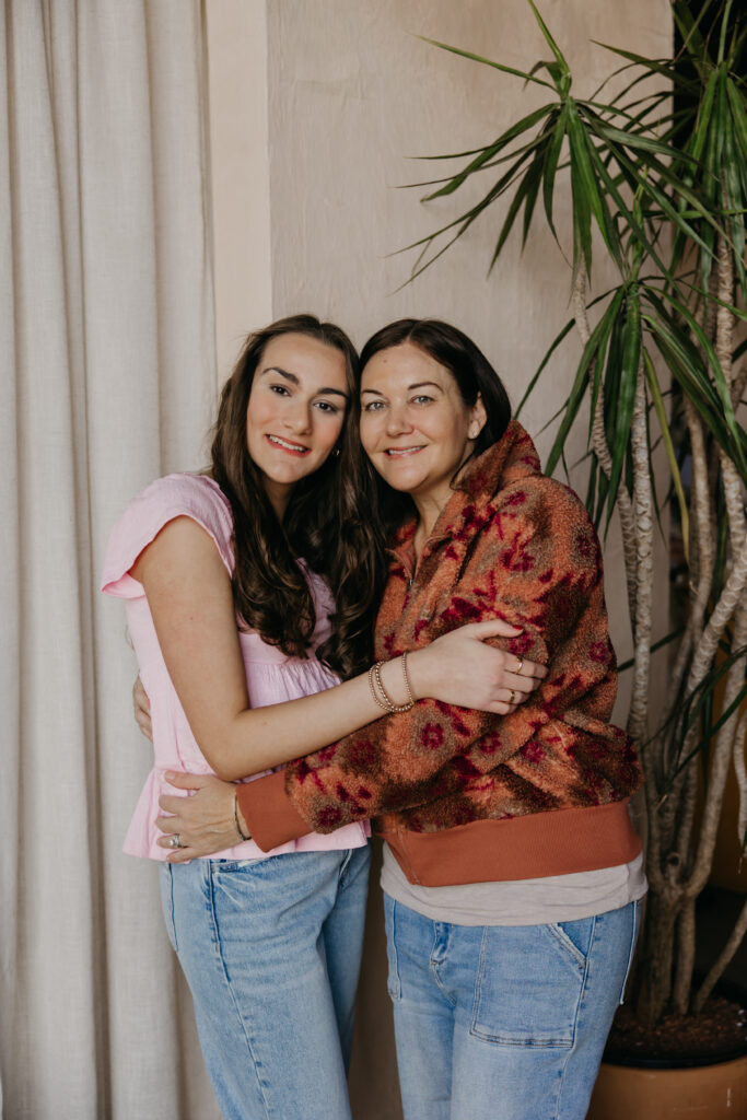 Minneapolis senior girl in pink top hugging her mom in a rust patterned cardigan during senior photography session with mom