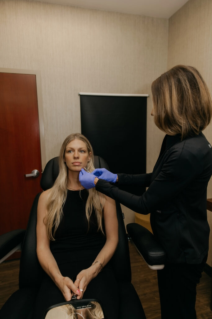Stephanie Astor administering a jawline injection to a client seated in the treatment chair at her Eden Prairie med spa