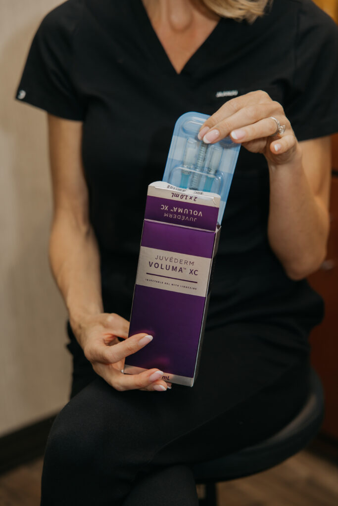 Hand holding a Juvederm Volux XC box while seated, med spa branding photo