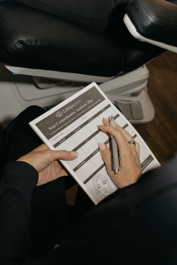 Close-up of a hand marking a facial assessment and treatment plan sheet, nurse injector consultation