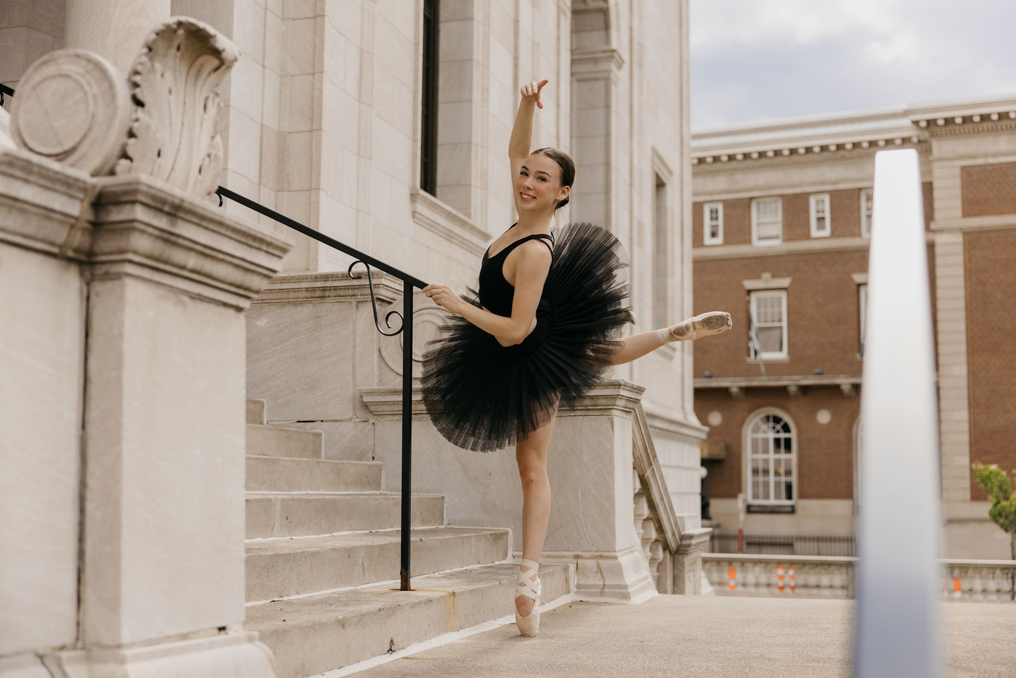 Senior dance photos for Minnesota ballet dancers, dancer in black tutu on pointe at a stone railing