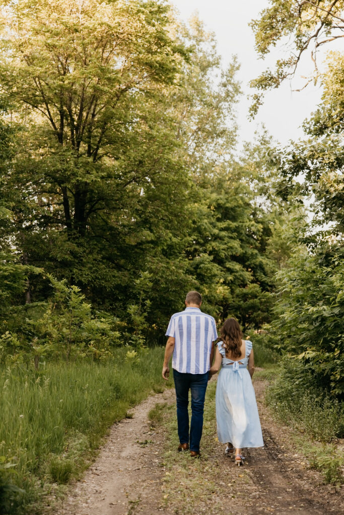 Couple walking away from camera down a wooded path