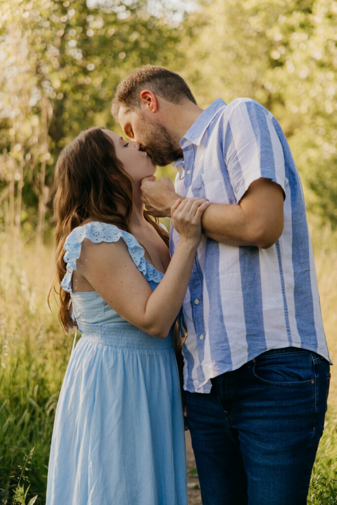Couple kissing outdoors, woman in blue striped dress, man in matching striped shirt