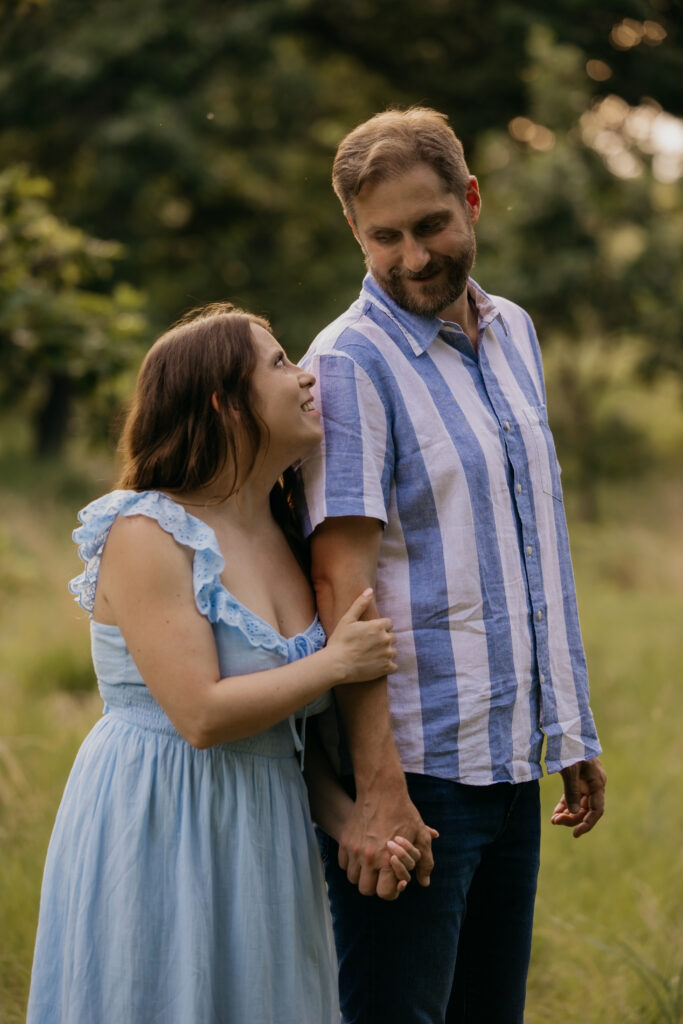 Woman looking up at man affectionately, both standing in a field