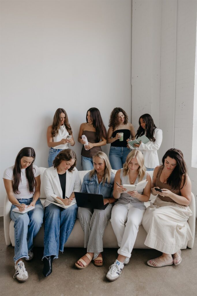 Group of women gathered on a couch with notebooks, brand photography for a coaching business